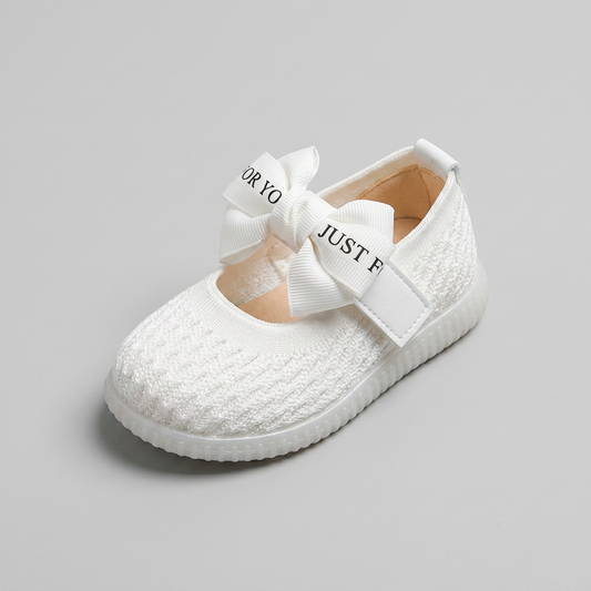 Three-quarter view of white knit baby Mary Jane flat showing bow detail and interior