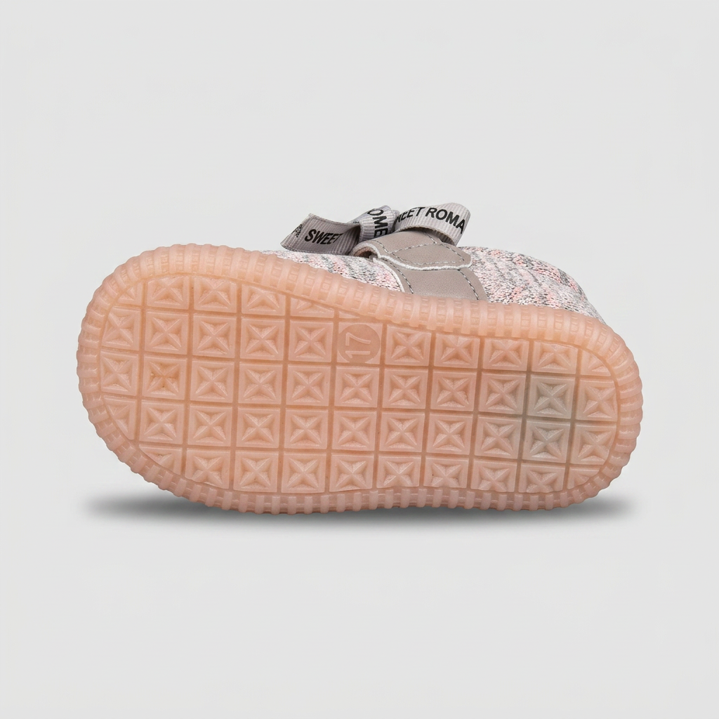 Underside tread pattern of a peach-colored baby shoe sole